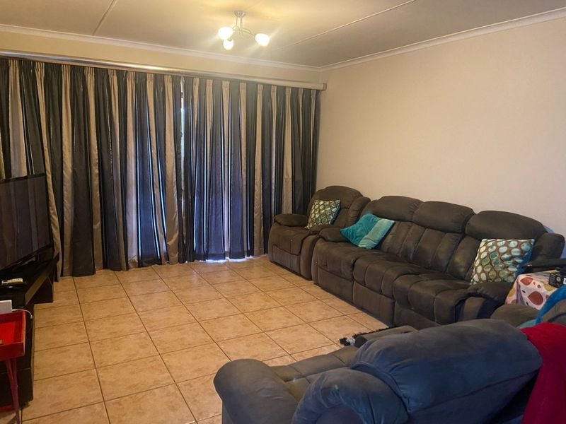 A living room featuring tiled flooring and ceiling coving, providing a functional space with direct access to an outdoor area via sliding doors.