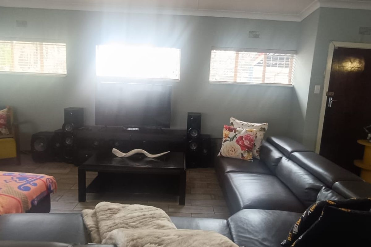 A comfortable living room featuring tiled flooring, multiple windows providing natural light, and a functional layout suitable for relaxation and entertainment.