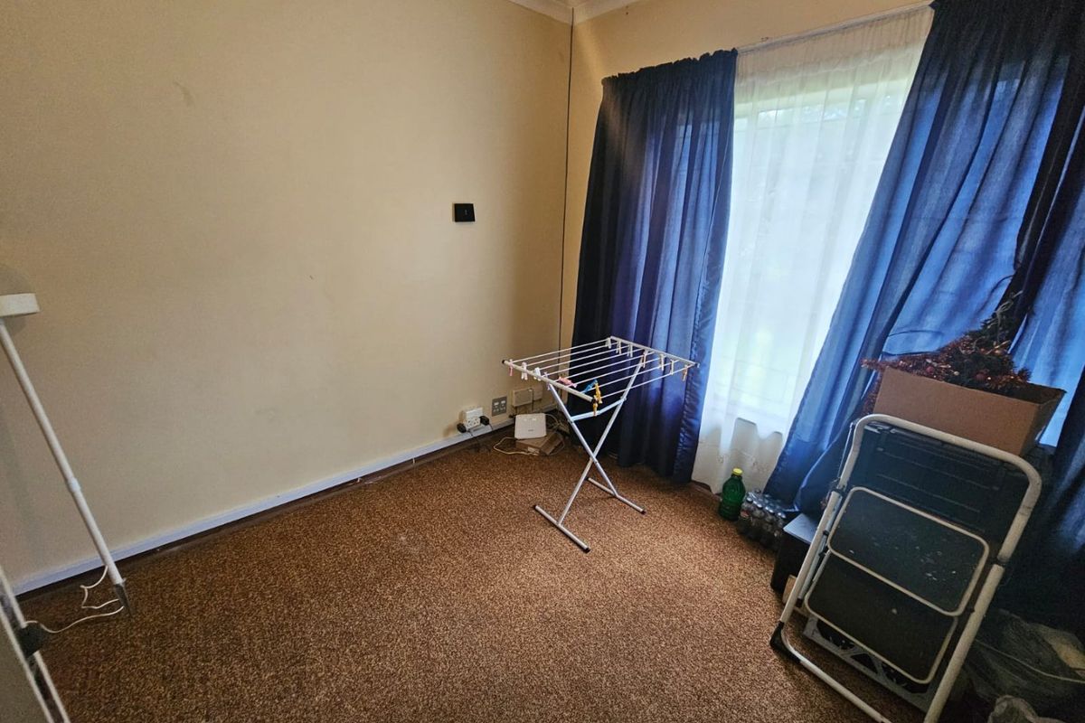 A bedroom featuring brown carpeting and a window with curtains, providing a blank canvas for potential interior updates.