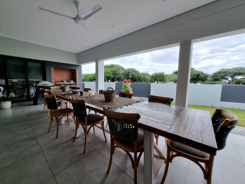 Spacious covered patio featuring tiled flooring, a built-in braai, and a ceiling fan, ideal for outdoor dining and entertaining.