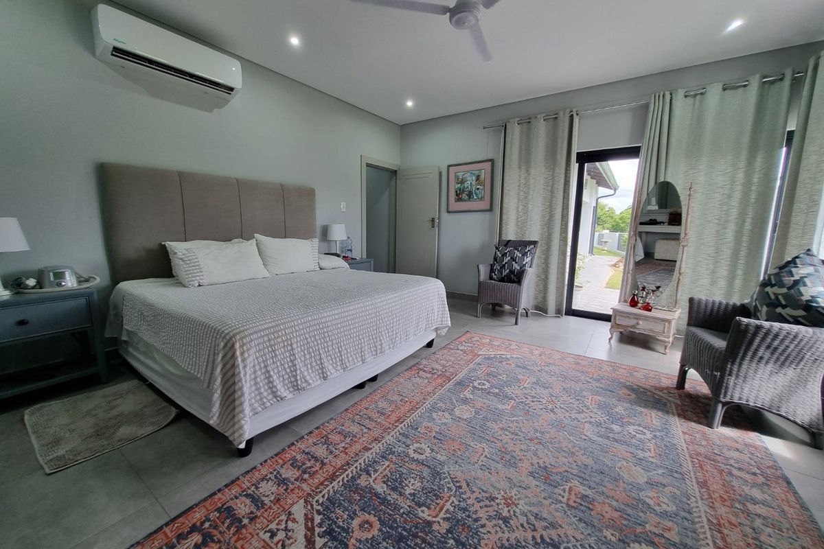 Spacious bedroom featuring tiled flooring, a ceiling fan, split-system air conditioning, and direct access to the outdoor area through a sliding glass door.