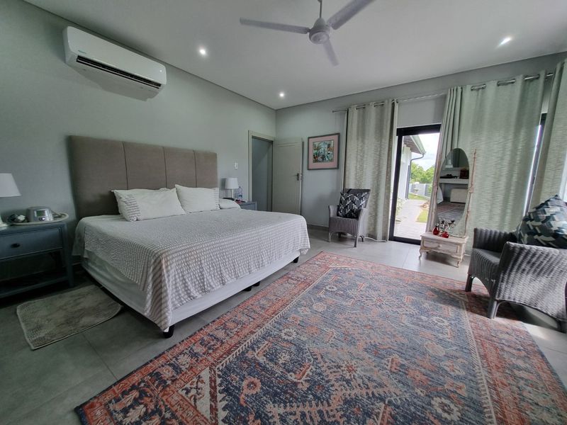 Spacious bedroom featuring tiled flooring, a ceiling fan, split-system air conditioning, and direct access to the outdoor area through a sliding glass door.