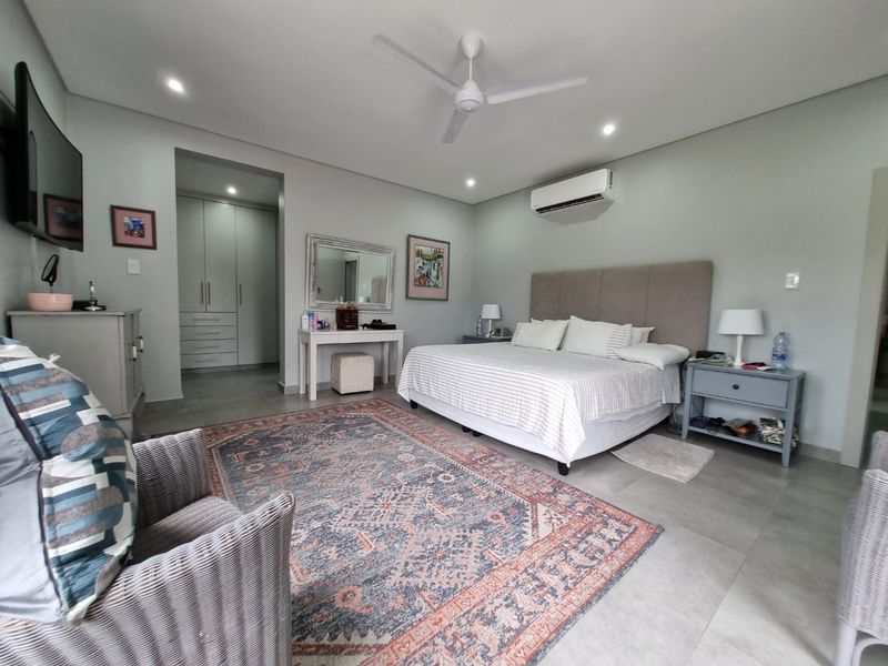 Spacious bedroom featuring tiled flooring, built-in cupboards, a ceiling fan, and a wall-mounted split-system air conditioner.