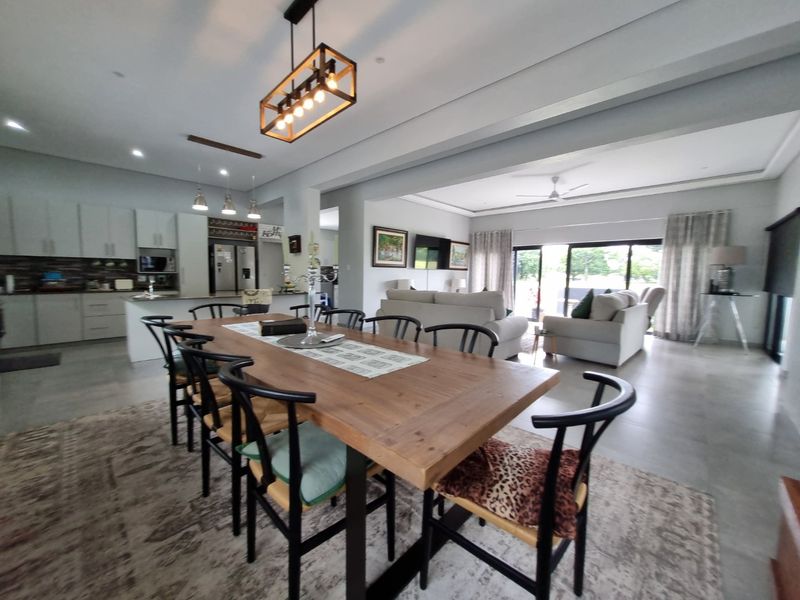 Spacious open-plan living and dining area featuring a modern kitchen with island, tiled floors, and large sliding doors leading to the outdoor space.