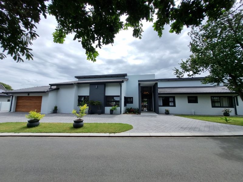 A modern, well-maintained single-story house featuring a paved driveway, double garage, and contemporary architectural design with a tiled roof.