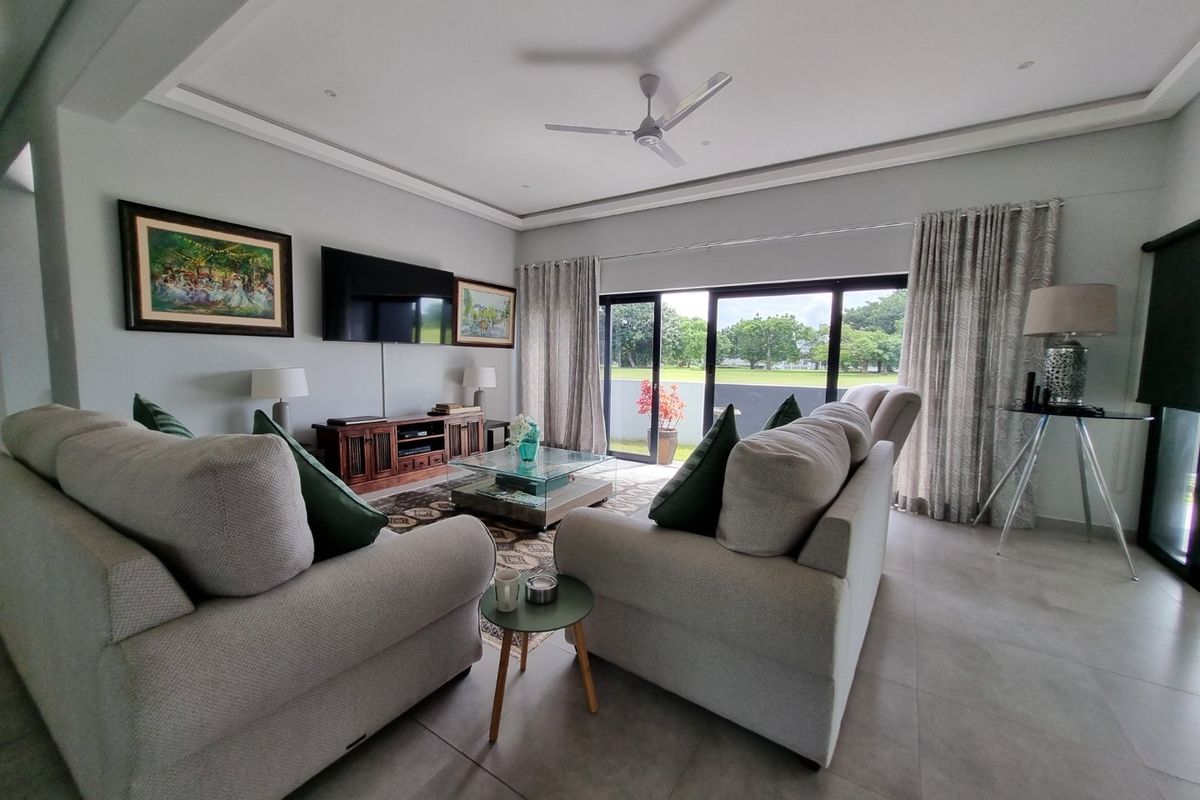 Spacious living room featuring tiled flooring, recessed lighting, a ceiling fan, and large sliding glass doors providing natural light and garden views.