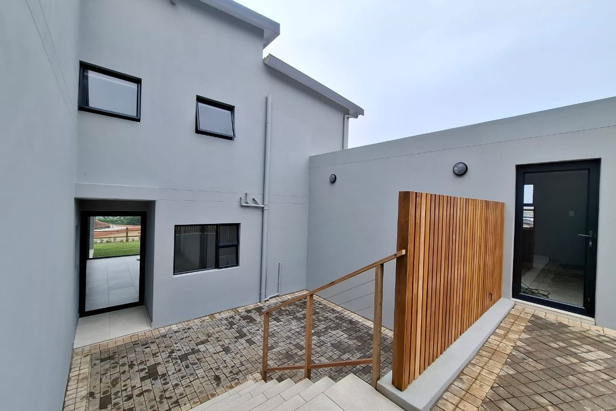 A modern rear courtyard area featuring paved flooring, a timber privacy screen, and external access points to the townhouse interior.