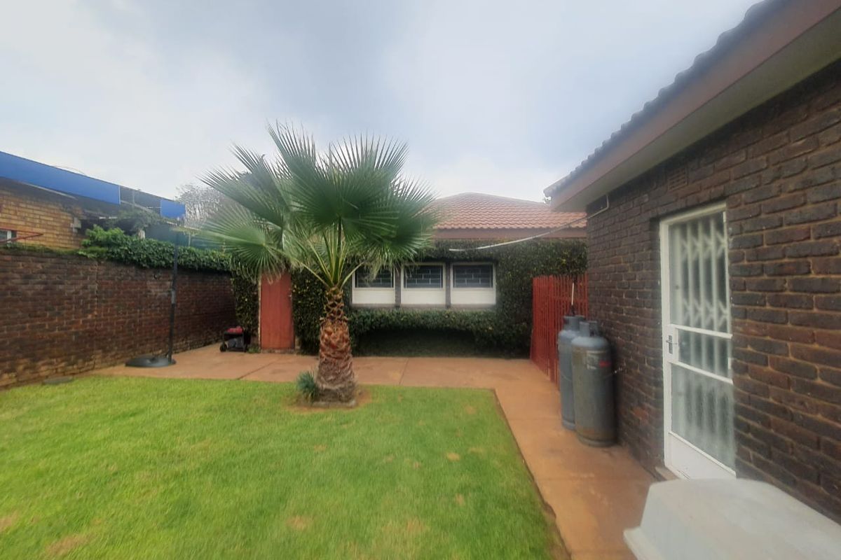 A private rear garden featuring a lawn, paved walkway, and brick boundary walls, providing a functional outdoor space for the property.