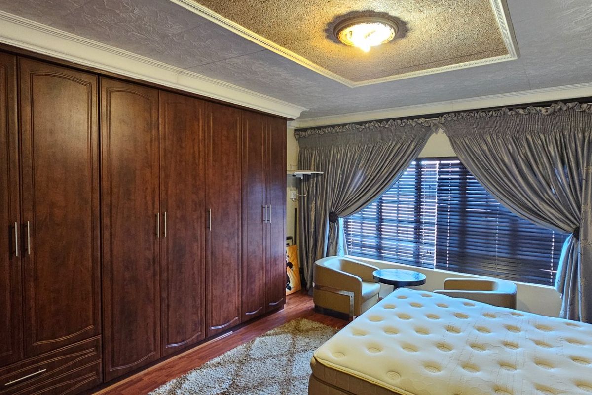 A bedroom featuring extensive built-in wooden cabinetry, a textured ceiling with a central light fixture, and a wall-mounted air conditioning unit.