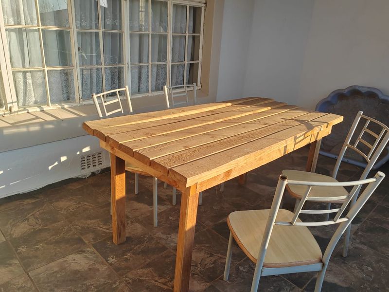 A covered patio area featuring tiled flooring and a large multi-pane window, providing a functional outdoor space for dining or relaxation.