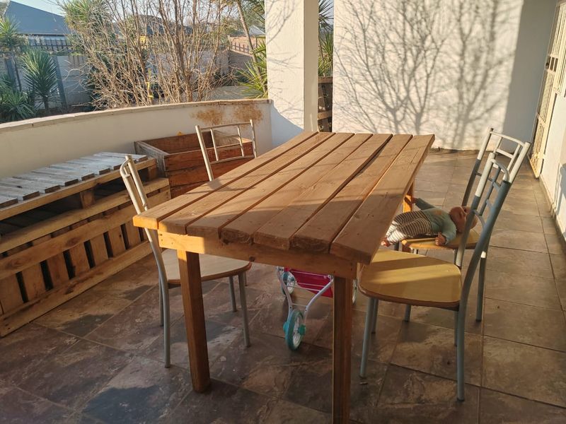 A covered patio area featuring tiled flooring and a low perimeter wall, providing an outdoor space suitable for relaxation or entertaining.