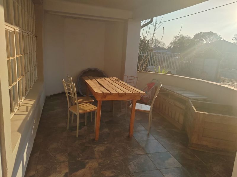 A covered patio area featuring tiled flooring and a low perimeter wall, providing an outdoor space suitable for relaxation or dining.
