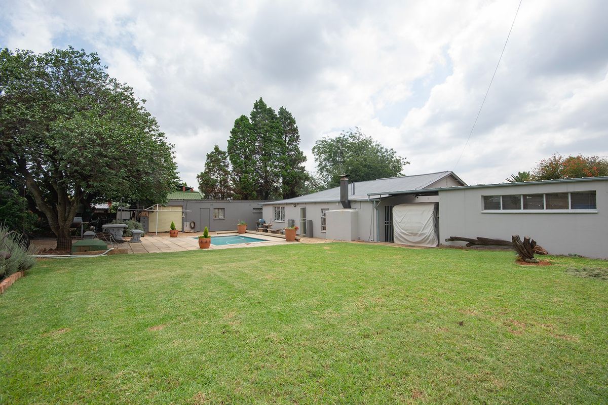 Spacious rear garden featuring a swimming pool, paved patio area, and established lawn, providing a private outdoor space for relaxation and entertainment.