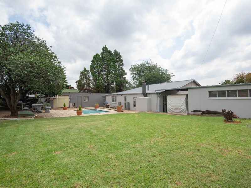 Spacious rear garden featuring a swimming pool, paved patio area, and established lawn, providing a private outdoor space for relaxation and entertainment.