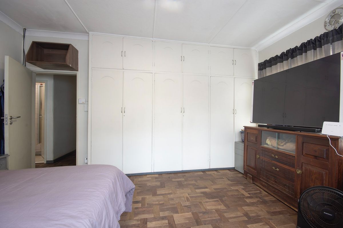 A bedroom featuring extensive built-in floor-to-ceiling cabinetry and traditional parquet wood flooring, providing ample storage space.