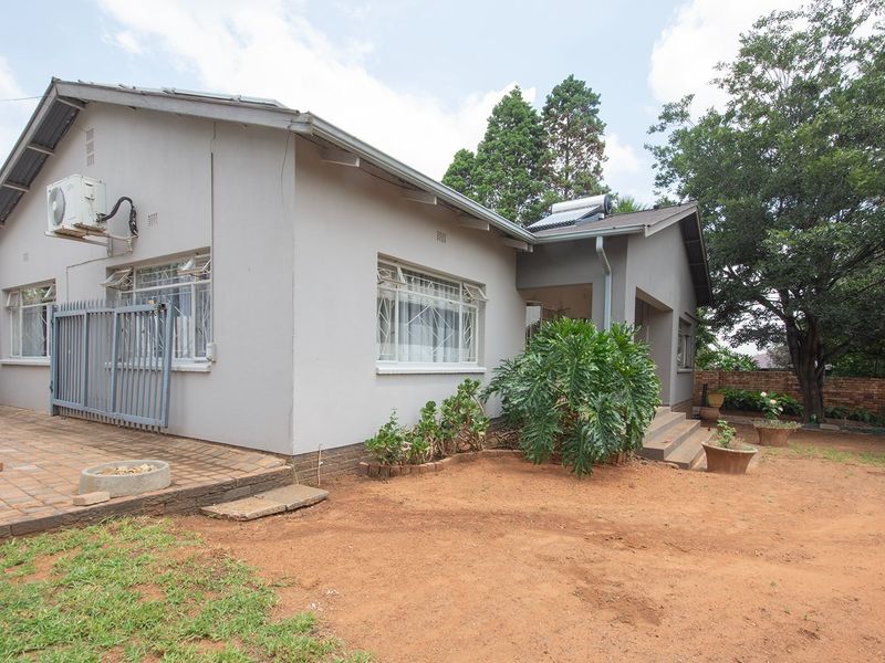 Rear view of the house featuring a paved patio area, solar water heating system, and established garden space.