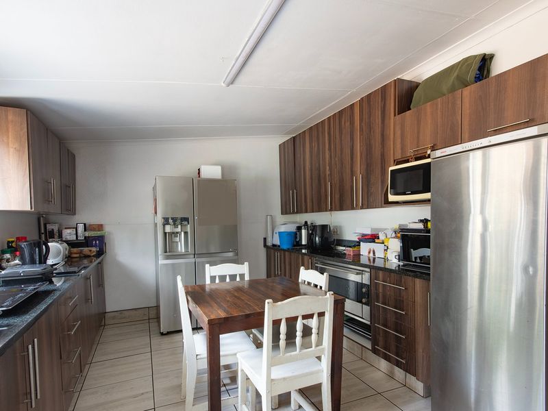 A functional kitchen featuring dark wood-grain cabinetry, granite countertops, built-in oven, and tiled flooring, providing a practical workspace for daily meal preparation.