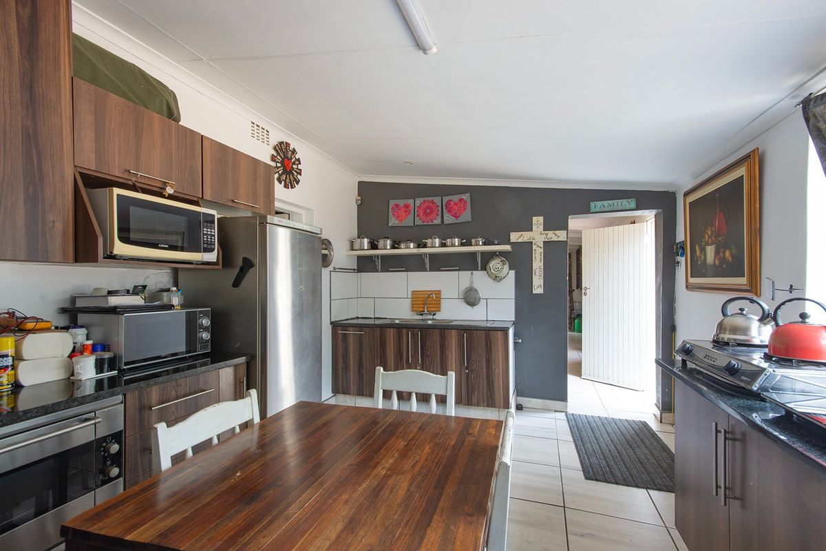Functional kitchen featuring dark wood-look cabinetry, granite countertops, tiled flooring, and integrated storage space with direct access to the exterior.