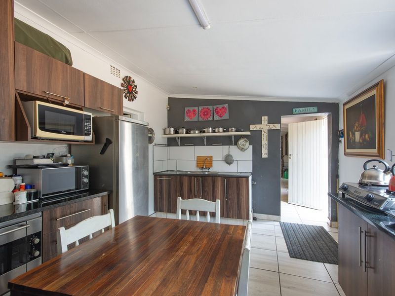 Functional kitchen featuring dark wood-look cabinetry, granite countertops, tiled flooring, and integrated storage space with direct access to the exterior.
