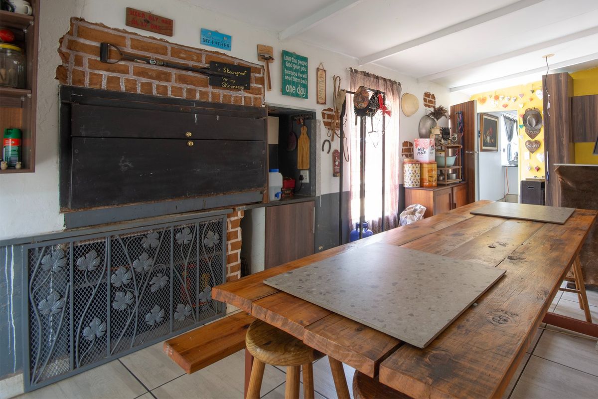 A rustic indoor entertainment area featuring a built-in brick fireplace with a metal screen and tiled flooring.