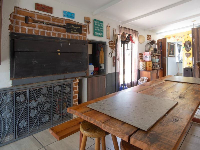 A rustic indoor entertainment area featuring a built-in brick fireplace with a metal screen and tiled flooring.