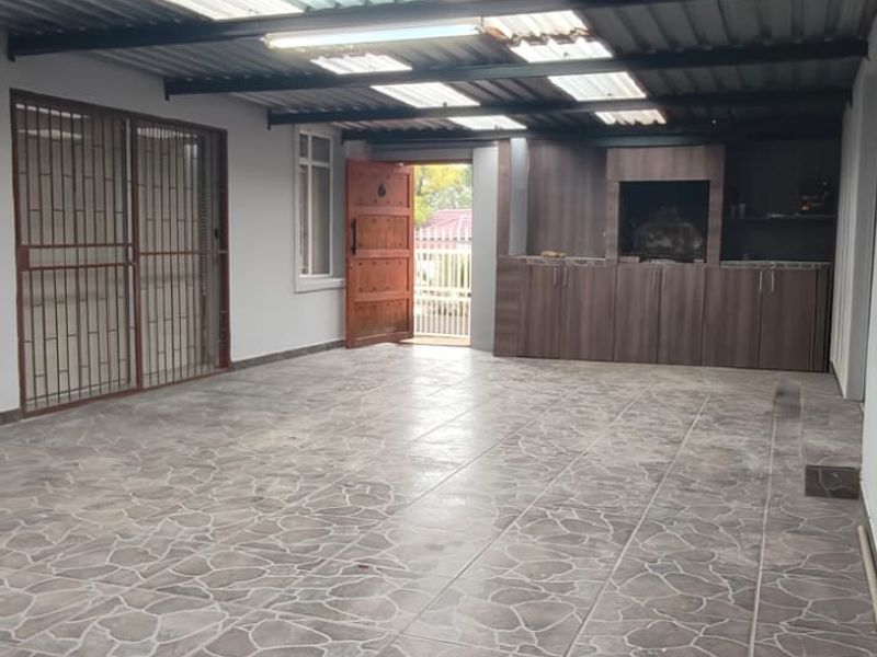Spacious covered patio featuring tiled flooring, built-in cabinetry, and a built-in braai, perfect for outdoor entertaining.