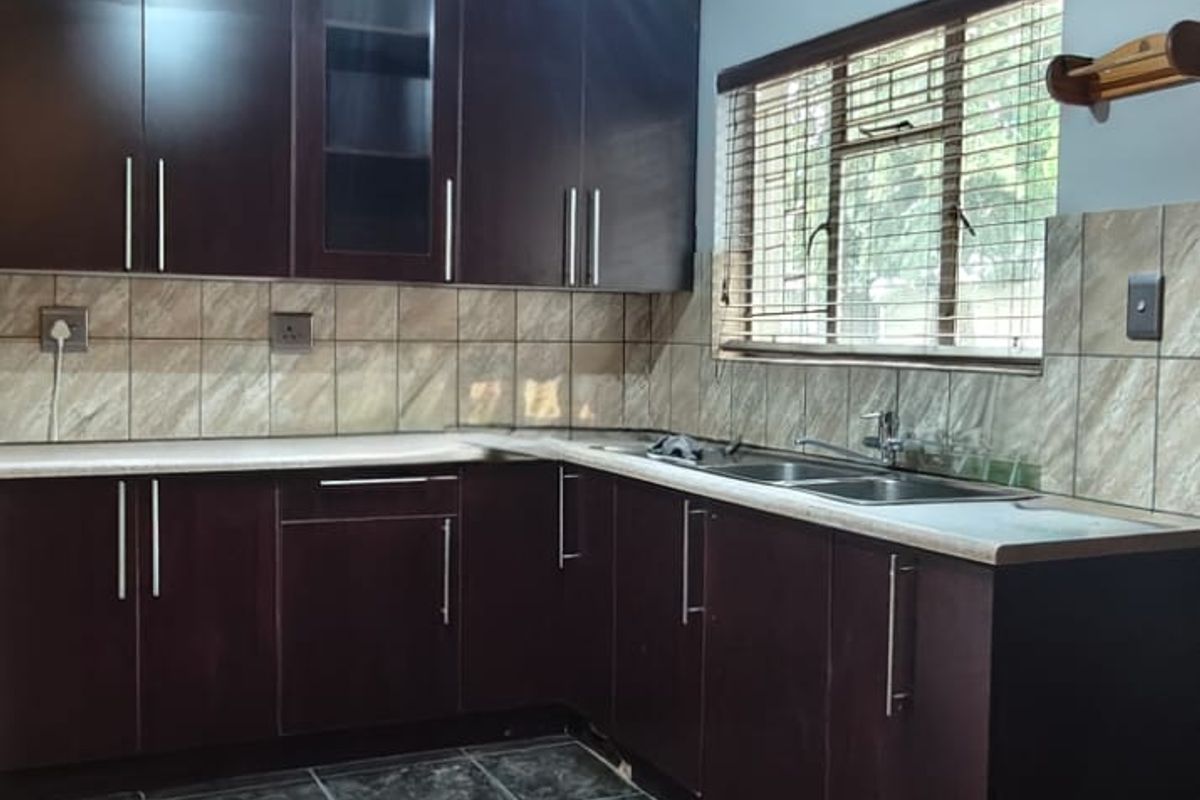 A functional kitchen featuring dark wood cabinetry, tiled backsplash, and dark floor tiles, offering a clean and practical workspace.