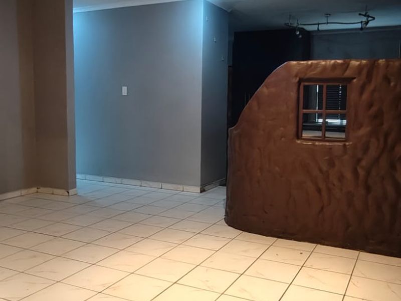 An open-plan living area featuring neutral wall tones, ceramic floor tiles, and a unique decorative partition wall.