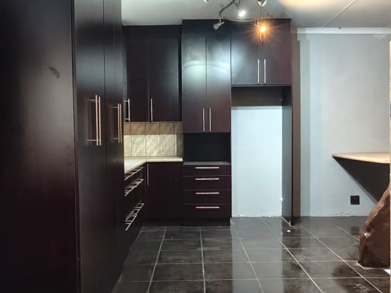 A modern kitchen featuring dark wood cabinetry, tiled flooring, and a built-in breakfast bar, offering a clean and functional space.
