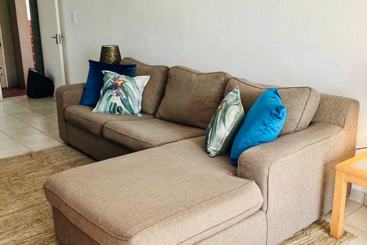 A living room area featuring neutral ceramic floor tiles and a ceiling fan, providing a functional and well-lit space.