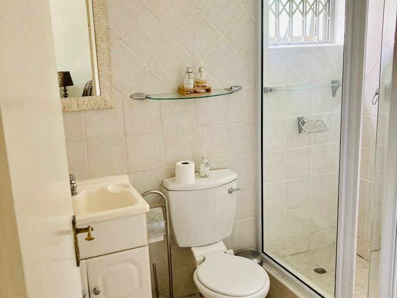Compact bathroom featuring a vanity cabinet, toilet, and a separate shower enclosure with tiled finishes throughout.