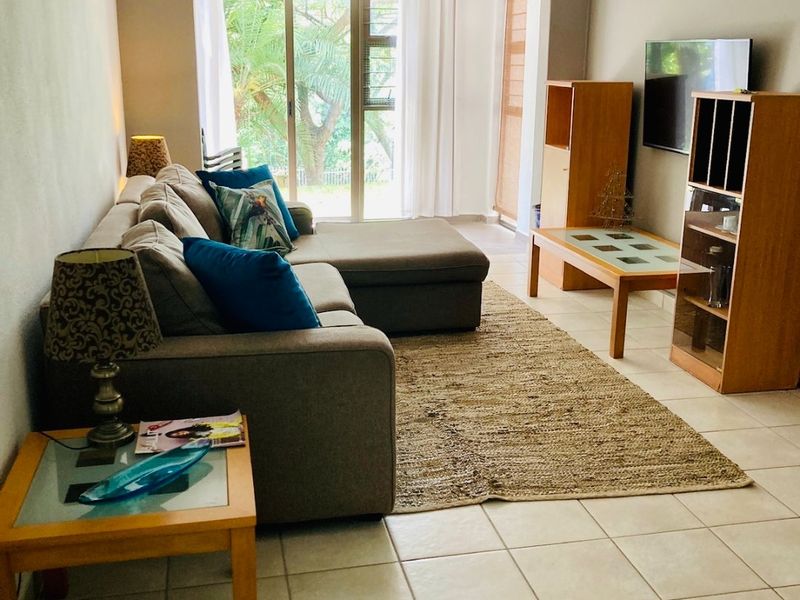 A comfortable living room featuring tiled flooring, a ceiling fan, and a sliding glass door providing access to the outdoor area.