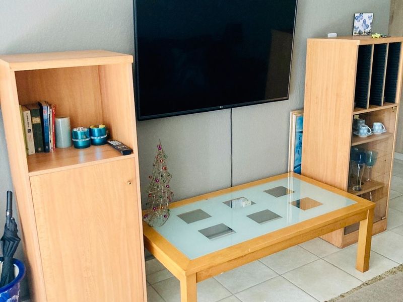 A living room area featuring tiled flooring and a wall-mounted television setup.