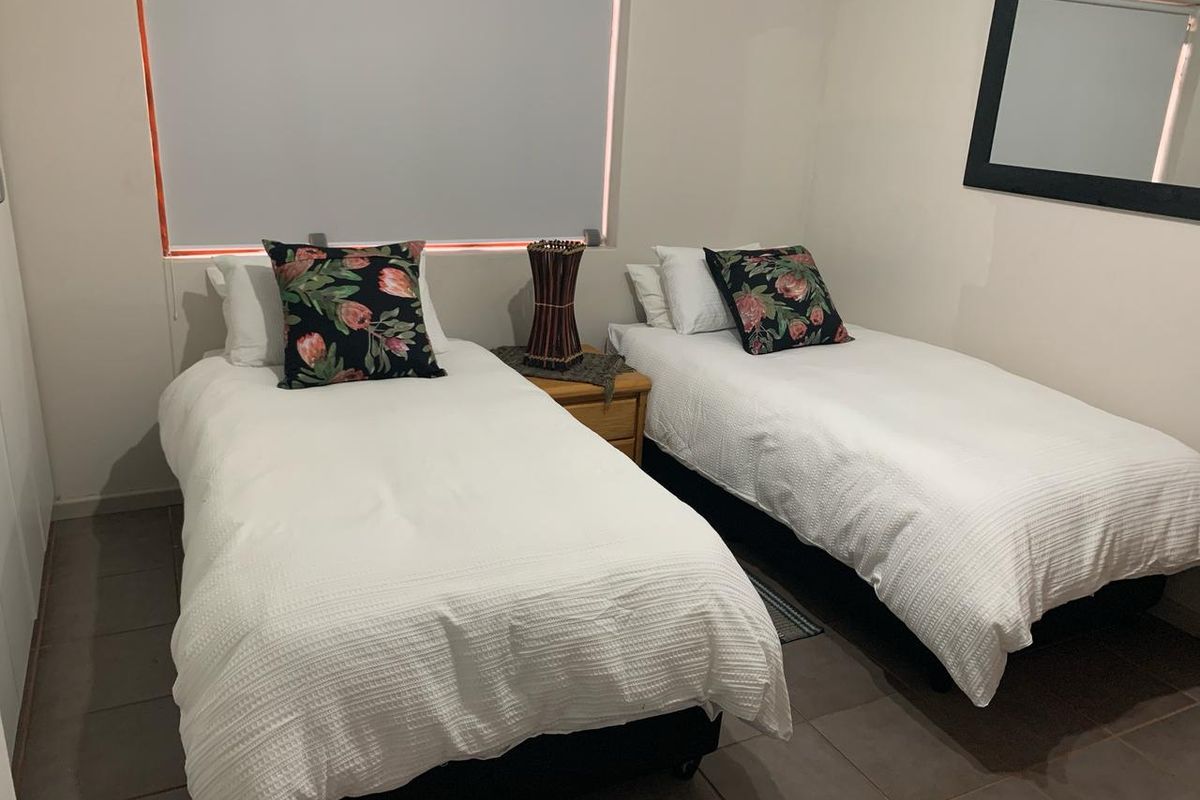 A bedroom featuring tiled flooring and a roller blind, currently configured with two single beds.