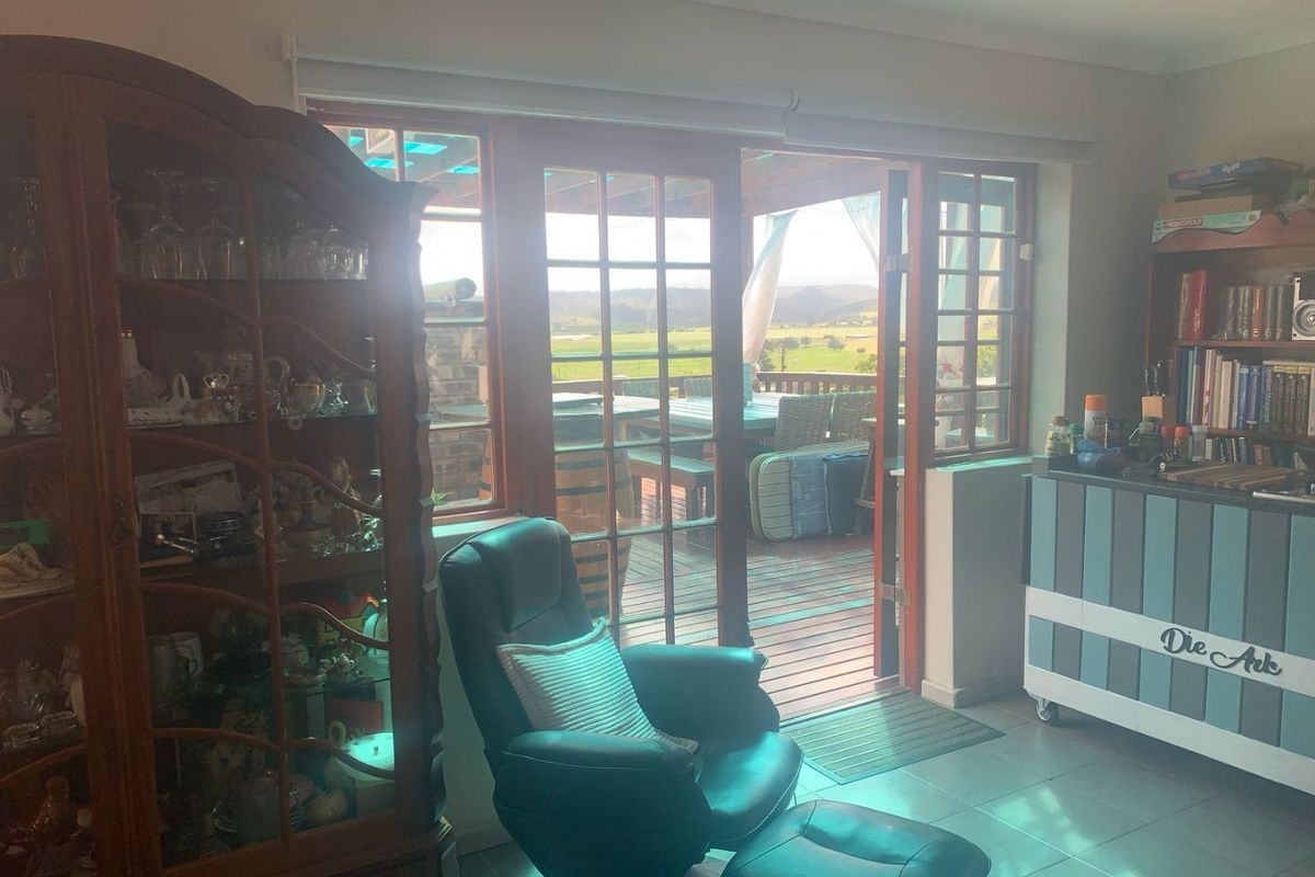 Living area featuring tiled flooring and timber-framed glass doors providing direct access to an outdoor deck with scenic rural views.