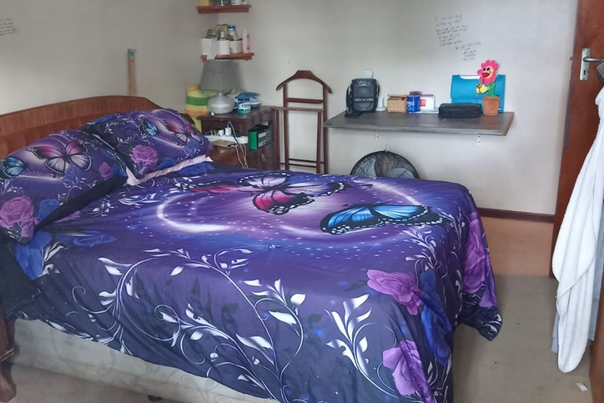 A standard bedroom featuring carpeted flooring, a wall-mounted desk, and built-in shelving, offering a functional space for rest or study.