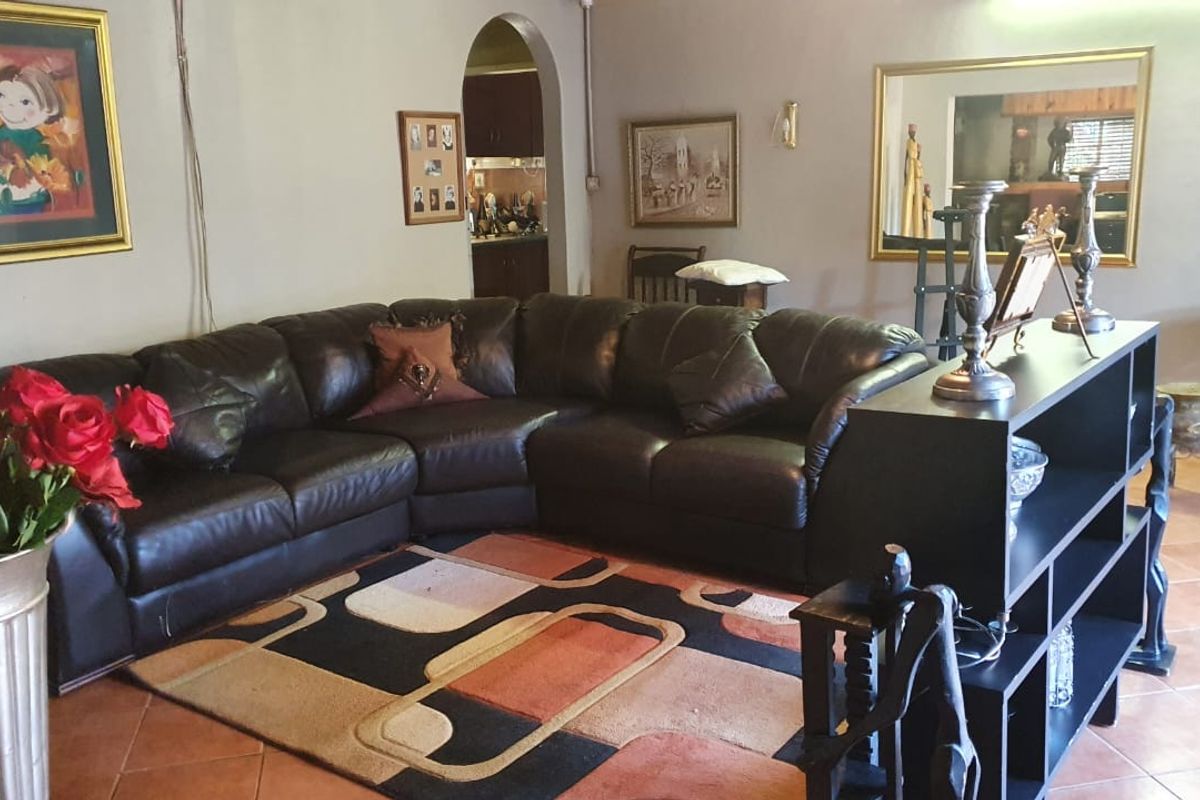 A living room featuring tiled flooring and an arched doorway leading to an adjacent space.