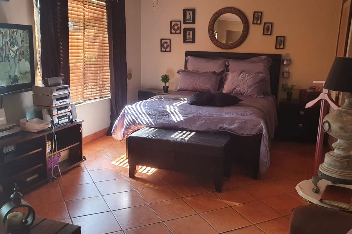 A bedroom featuring terracotta floor tiles and natural light through wooden blinds.