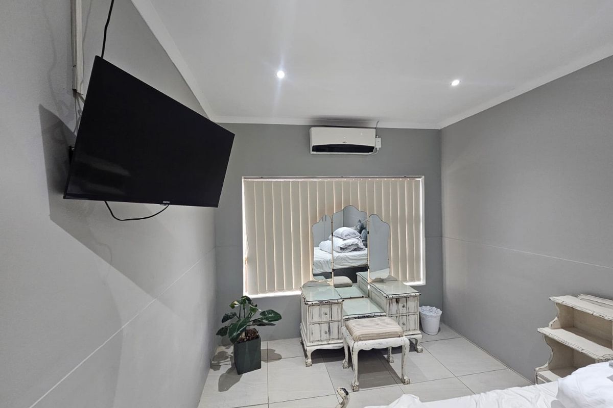 A bedroom featuring tiled flooring, recessed ceiling lighting, and a wall-mounted air conditioning unit.