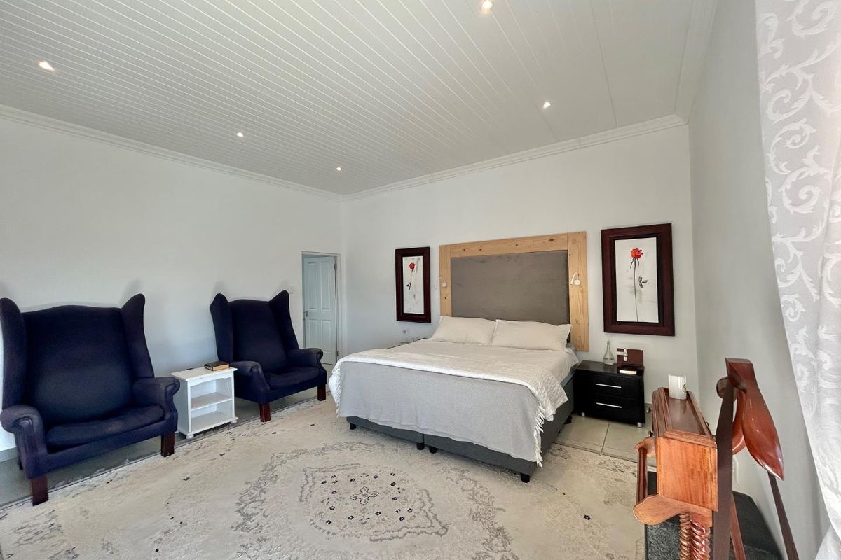 Spacious bedroom featuring a white tongue-and-groove ceiling with recessed lighting and neutral tiled flooring.