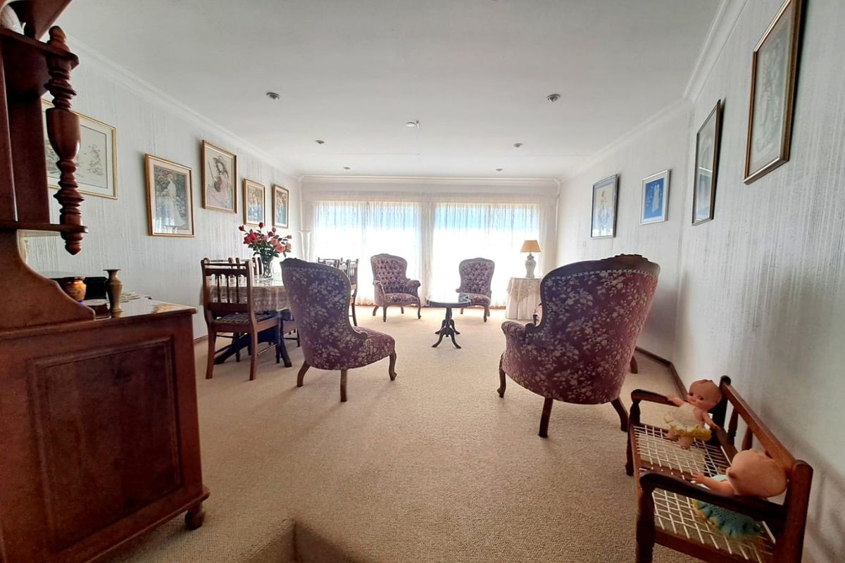 A spacious living area featuring neutral carpeting, recessed ceiling lighting, and large windows that provide ample natural light.