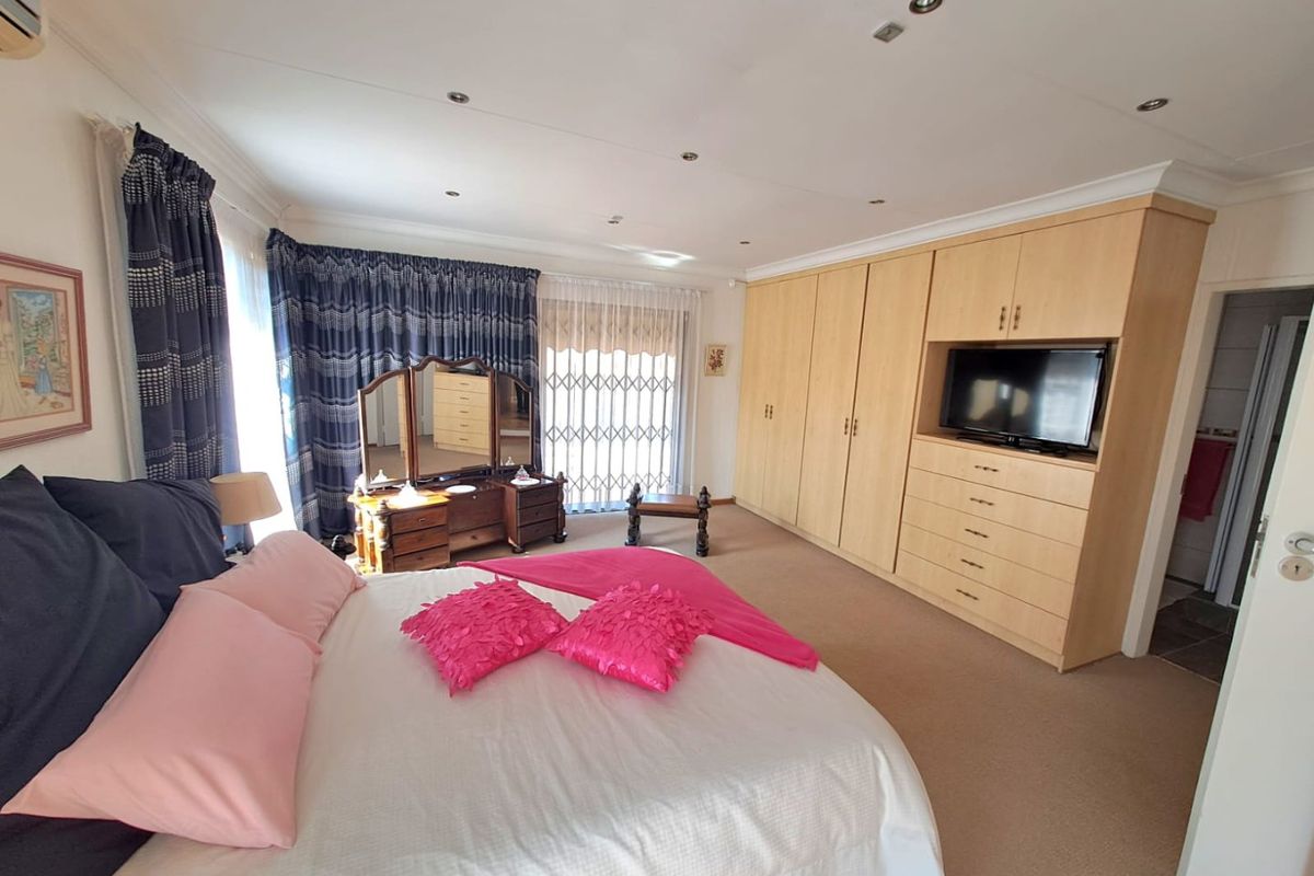 Spacious bedroom featuring extensive built-in wooden cabinetry, recessed ceiling lighting, and a security gate leading to an outdoor area.