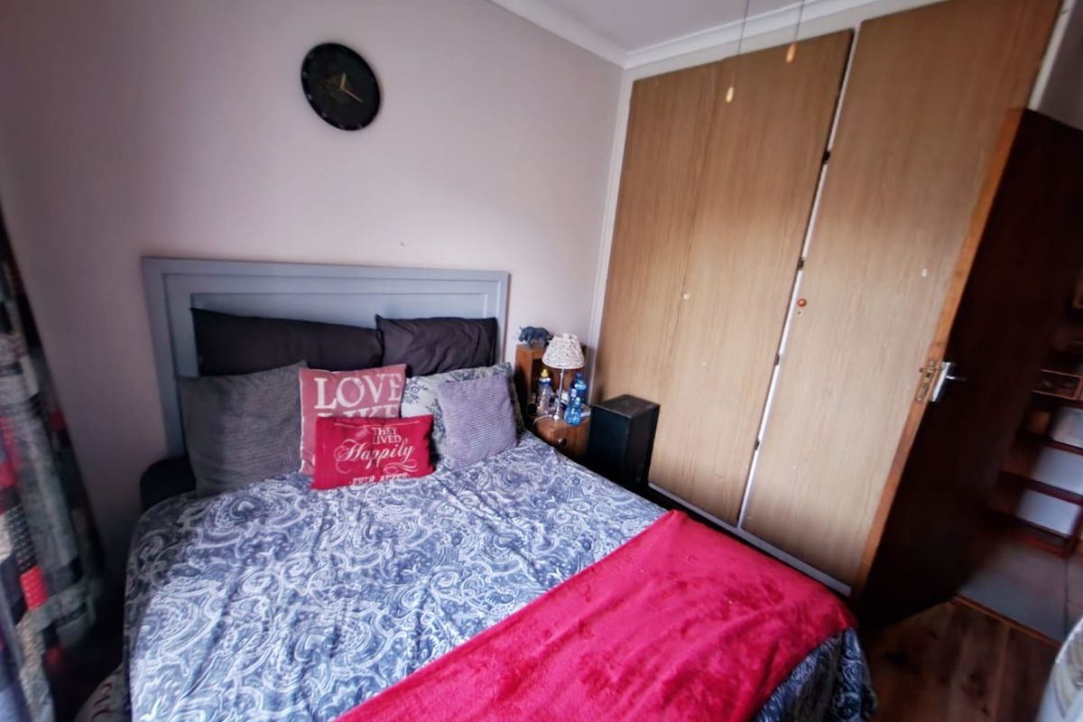 A functional bedroom featuring built-in wooden wardrobes and laminate flooring, providing a practical and comfortable living space.