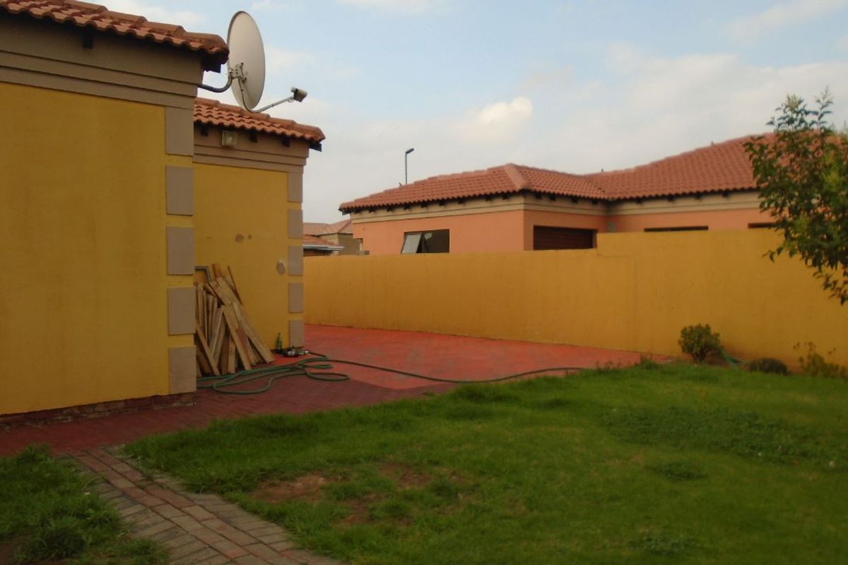A rear garden area featuring a paved patio, lawn, and perimeter boundary walls, providing a private outdoor space for the property.