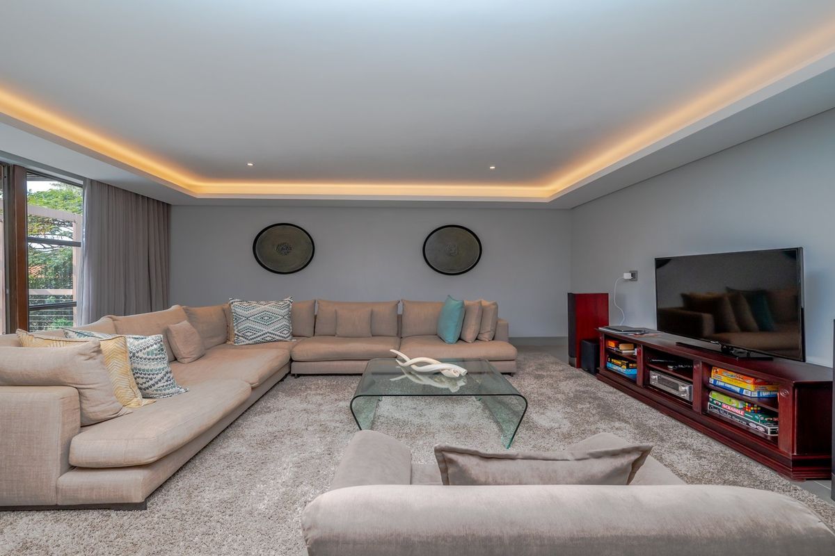 Spacious living room featuring recessed cove lighting, neutral finishes, and large sliding glass doors providing access to the outdoor area.