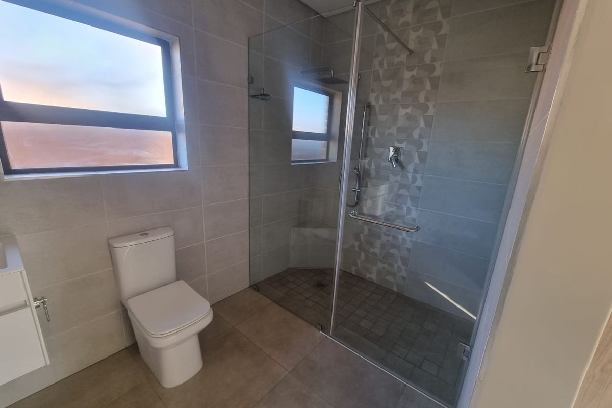 Modern bathroom featuring a frameless glass walk-in shower with mosaic tile accents, a wall-mounted vanity, and a contemporary toilet.