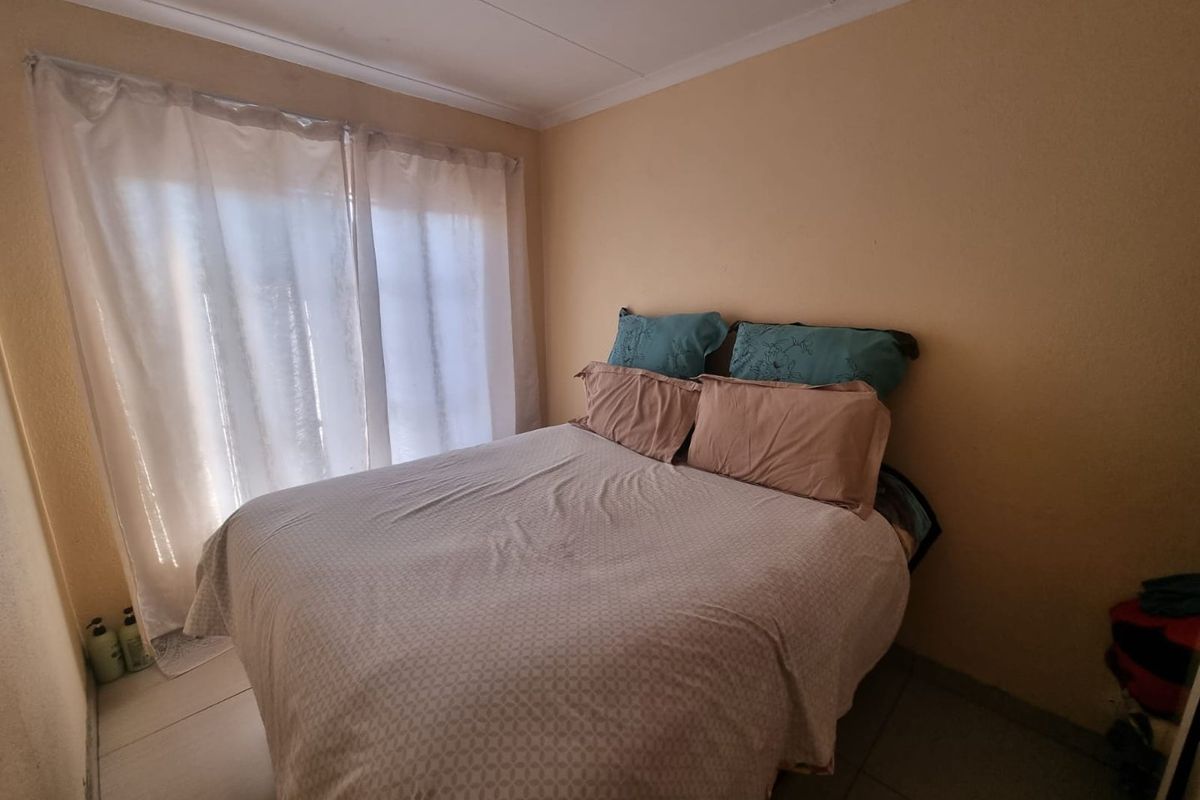 A functional bedroom featuring tiled flooring and sliding glass doors that provide natural light and access to the exterior.