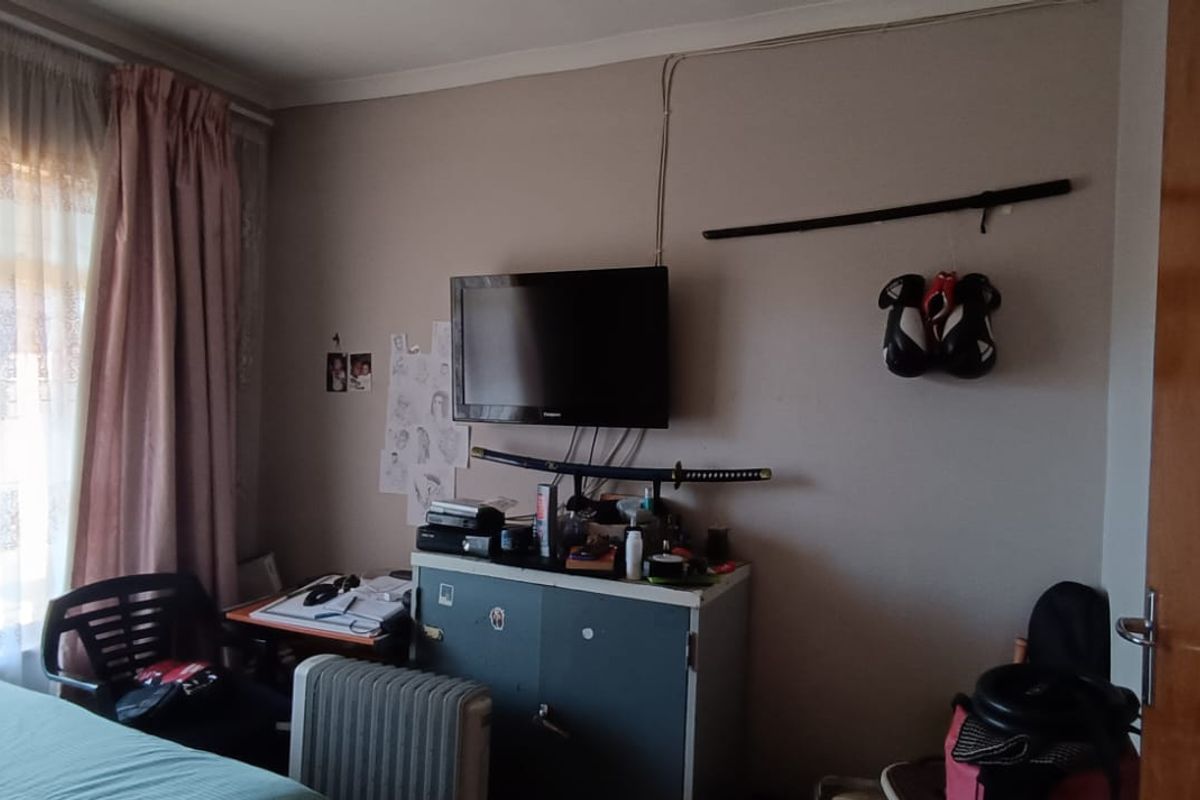 A standard bedroom featuring a window with curtains and a solid core interior door.