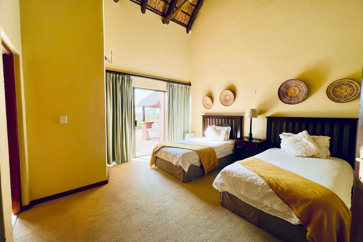 Spacious bedroom featuring high exposed thatch ceilings, carpeted flooring, and a sliding glass door providing direct access to an outdoor patio area.