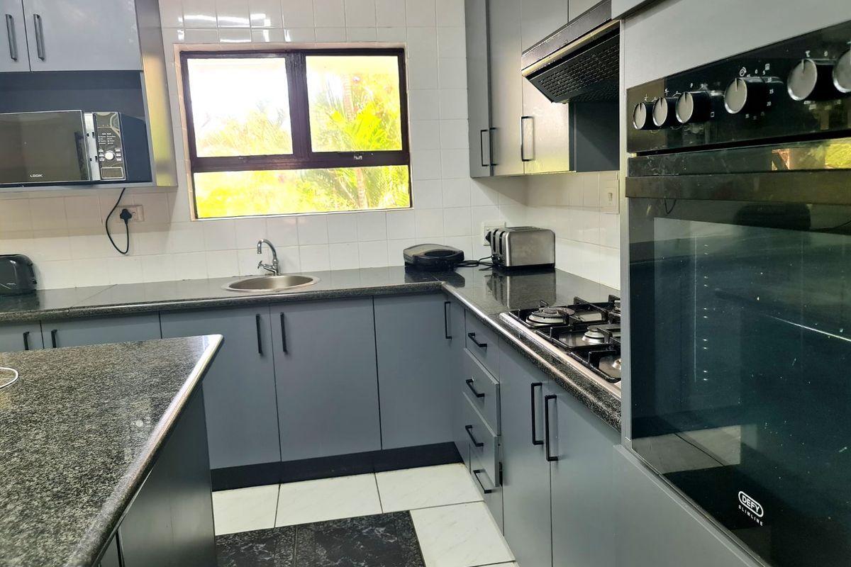 Modern kitchen featuring grey cabinetry, granite countertops, a built-in oven, gas hob, extractor fan, and tiled flooring.